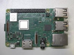 Board Raspberry Pi 3 Model B+ nhìn từ trên xuống, thấy nắp kim loại logo Raspberry và các cổng USB, LAN